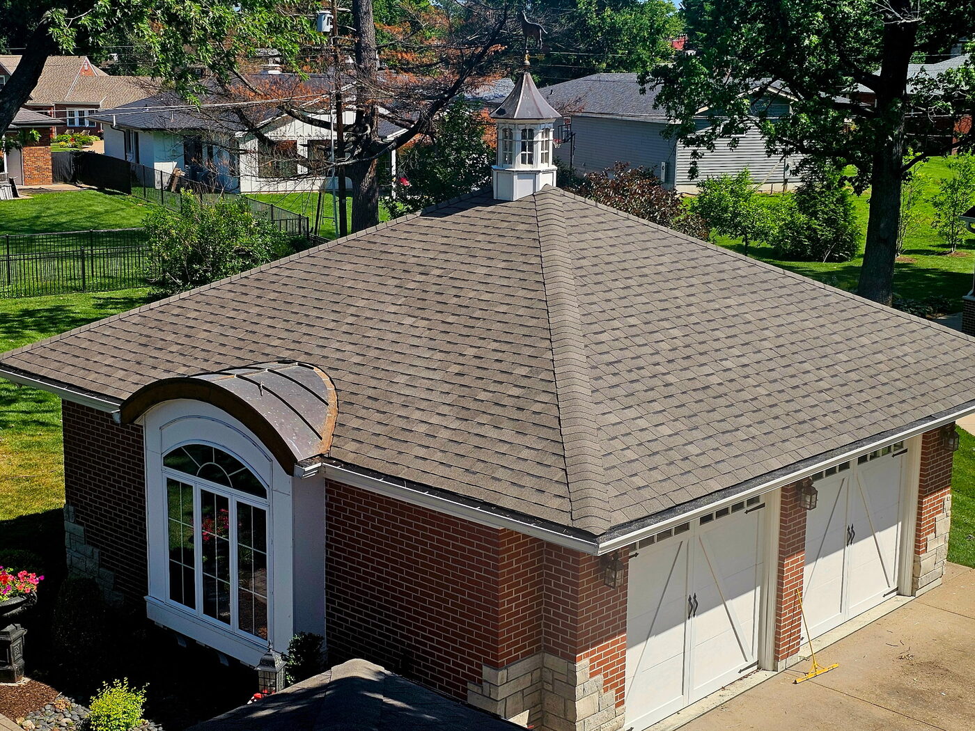 Completed architectural asphalt shingle hip roof on a brick home with copper accents