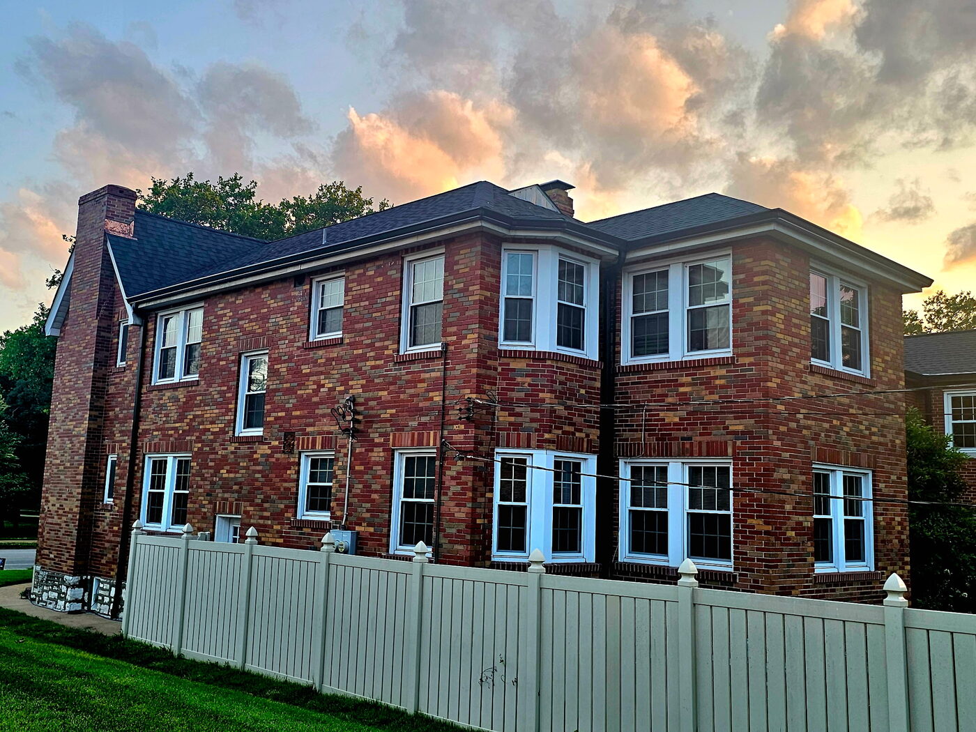 Finished two-story brick home photographed at dusk showing a completed Upward Roofing project