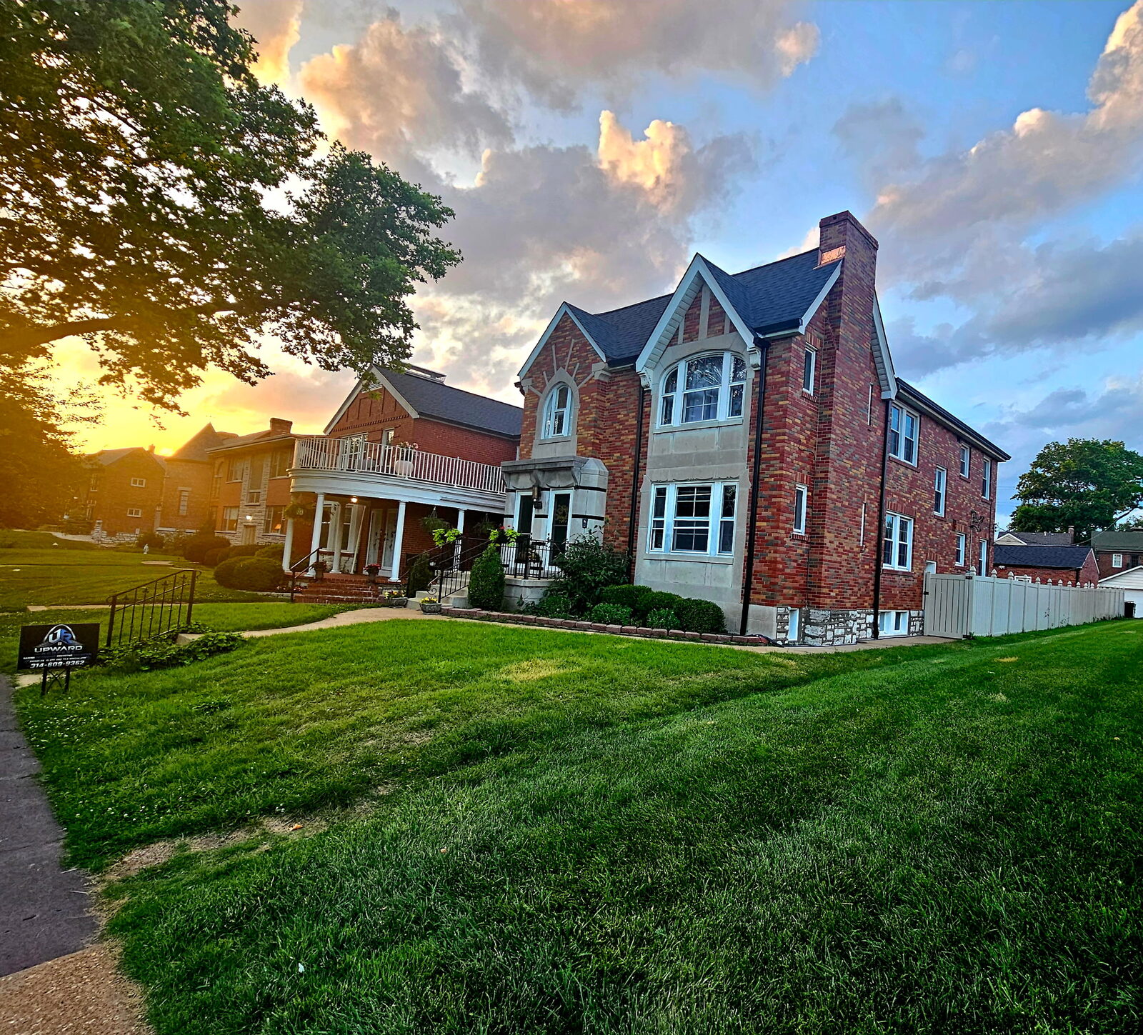 Completed brick home at golden hour with a finished roof against a dramatic St. Louis sunset sky